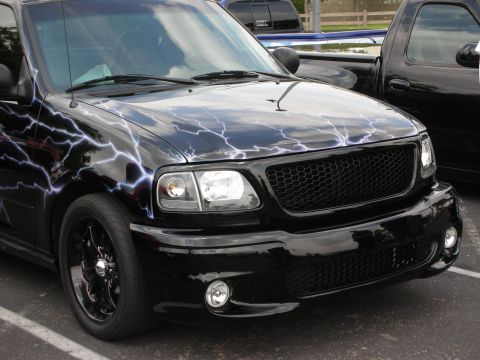 1992 Ford Crown Victoria - A black pickup truck with a custom lightning bolt paint job is parked next to another black truck.