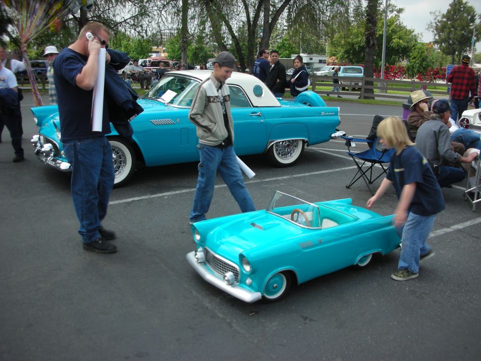 Full-size turquoise 1955 Ford Thunderbird and a matching miniature version parked side-by-side