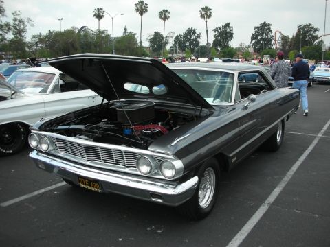 1992 Ford Crown Victoria - A dark gray 1962 Ford Galaxie is parked with its hood up at an outdoor car show.