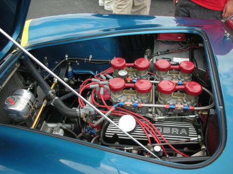 1992 Ford Crown Victoria - The engine bay of a blue Cobra reveals its V8 engine with prominent red carburetor tops and spark plug wires.