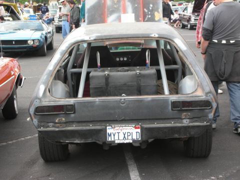 1992 Ford Crown Victoria - A heavily modified hatchback with a roll cage and racing fuel cell is parked at an outdoor car show.