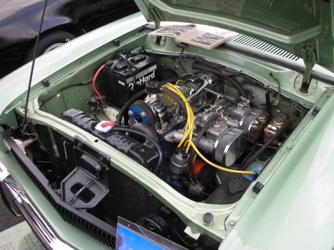 1992 Ford Crown Victoria - The engine bay of a light green car is open, revealing a V8 engine with chrome accents and dual carburetors.