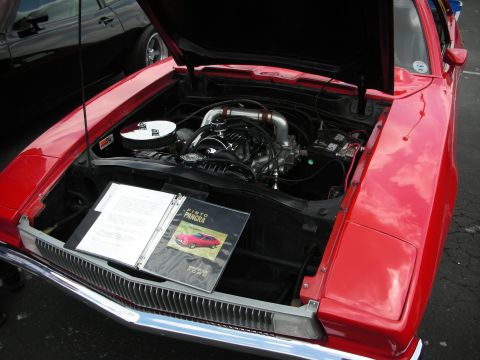 1992 Ford Crown Victoria - Engine bay of a red car, open hood reveals engine and a binder with car information.