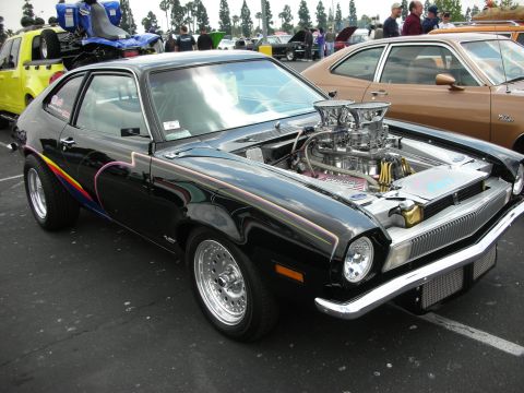1992 Ford Crown Victoria - A modified black coupe with a prominent V8 engine is parked at an outdoor car show.
