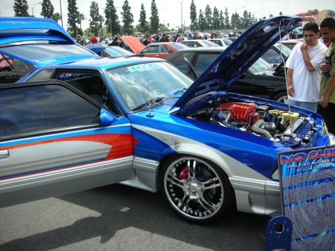 1992 Ford Crown Victoria - Modified Ford Mustang on display at a car show, with its hood open and a descriptive sign.