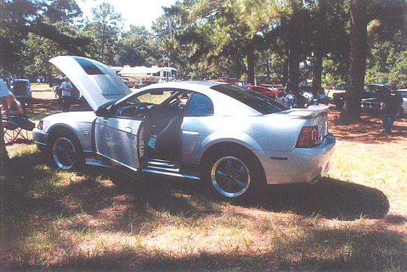Silver coupe with hood and driver door open, 3/4 front view