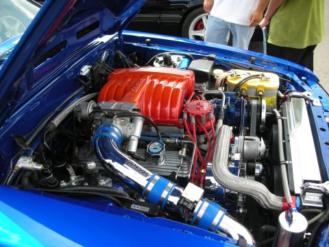 1992 Ford Crown Victoria - The engine bay of a blue car is shown with custom modifications and bright red components.