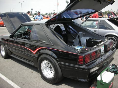1992 Ford Crown Victoria - Modified black Ford Mustang hatchback with racing modifications, seen at a car show.