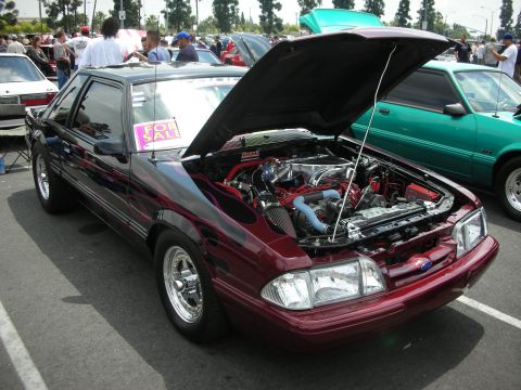 1992 Ford Crown Victoria - A customized Ford Mustang is displayed with its hood open, revealing the engine bay. A 'For Sale' sign is visible on the windshield.