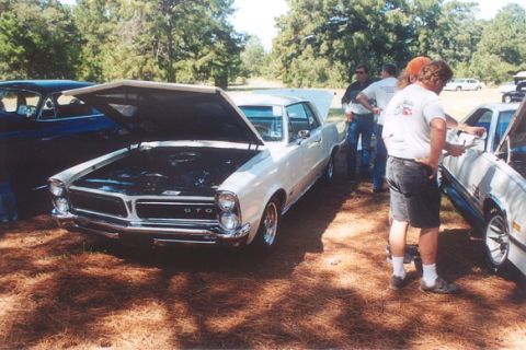 2002 Ford Crown Victoria - A 1965 Pontiac GTO is displayed with its hood open at an outdoor car show.