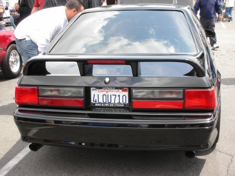 1992 Ford Crown Victoria - Rear view of a black Ford Mustang hatchback at a car show.