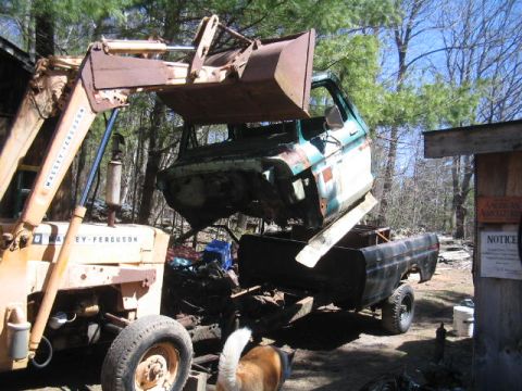 1979 Ford Bronco - A Massey-Ferguson tractor is lifting the cab off a pickup truck, with the truck's bed visible below.