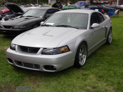1992 Ford Crown Victoria - A silver 2001 Ford Mustang Cobra is displayed at an outdoor car show with other vehicles.
