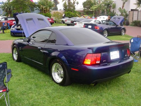 1992 Ford Crown Victoria - A dark purple Ford Mustang is displayed at an outdoor car show with other vehicles.