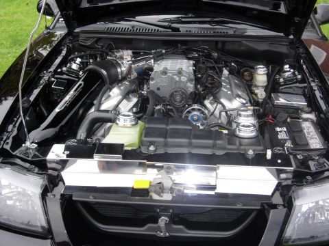 1992 Ford Crown Victoria - Customized engine bay a supercharged V8 and chrome details, with a Cobra emblem visible.