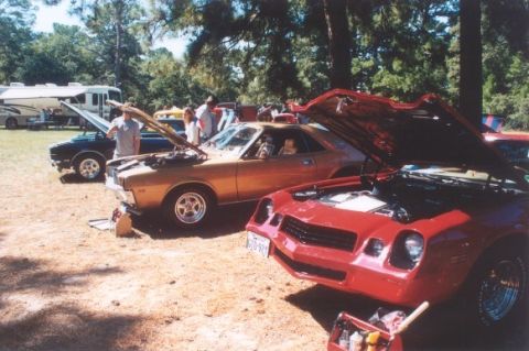 2002 Ford Crown Victoria - Multiple cars are displayed outdoors with their hoods open, including a red sports car in the foreground.