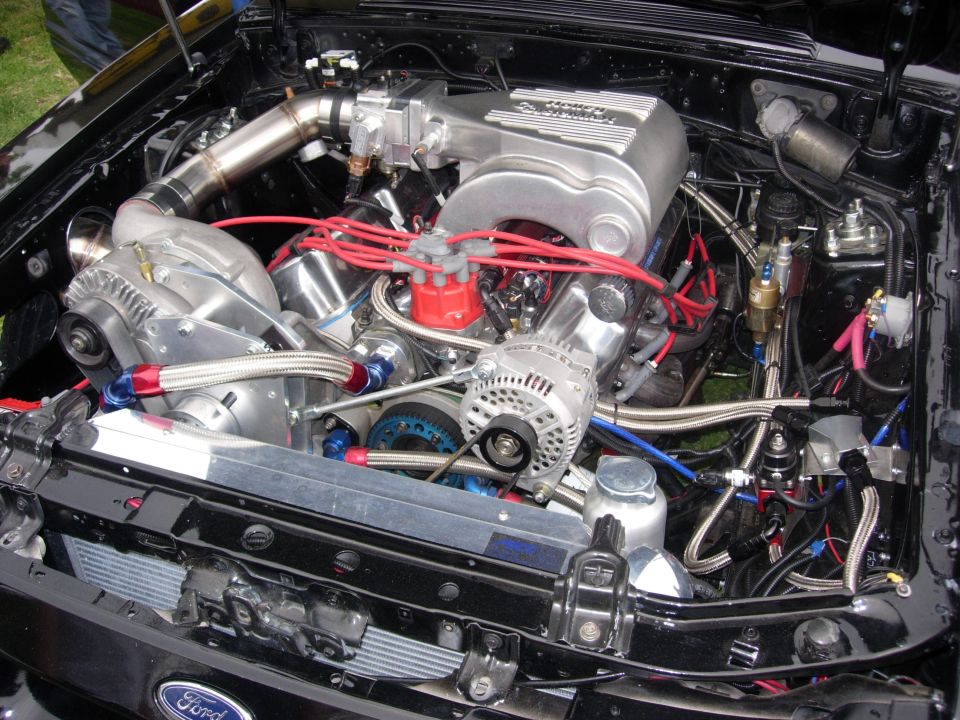 Engine bay with polished supercharger, red spark plug wires, and braided fuel lines