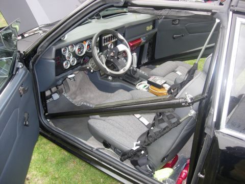1992 Ford Crown Victoria - This modified car's interior features racing seats, a roll cage, and an array of gauges, with a '5.0' badge on the dash.
