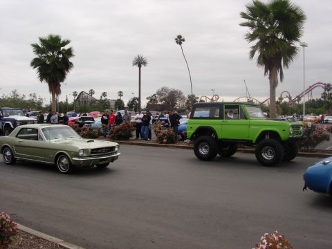 1992 Ford Crown Victoria - A lifted green Ford Bronco is seen at a car show with other classic vehicles and palm trees.