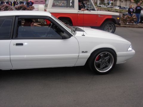 1992 Ford Crown Victoria - White Ford Mustang coupe driving alongside a red and white Ford Bronco.