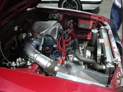 1992 Ford Crown Victoria - The engine bay of a custom car is shown, aftermarket performance parts and a prominent Ford logo on the oil cap.