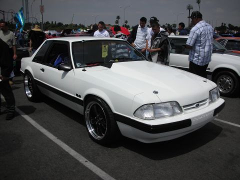 1992 Ford Crown Victoria - This white Ford Mustang, likely from the early 1990s, is on display at a car show.