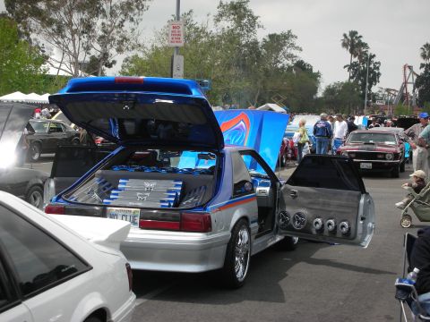 1992 Ford Crown Victoria - This customized Ford Mustang features extensive audio equipment in the trunk and doors, with other vehicles and attendees visible.