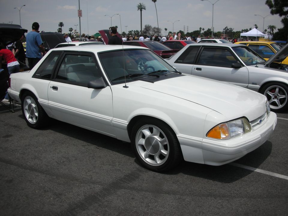 White coupe with a sunroof, viewed from the front three-quarter angle, showing its side profile and front fender