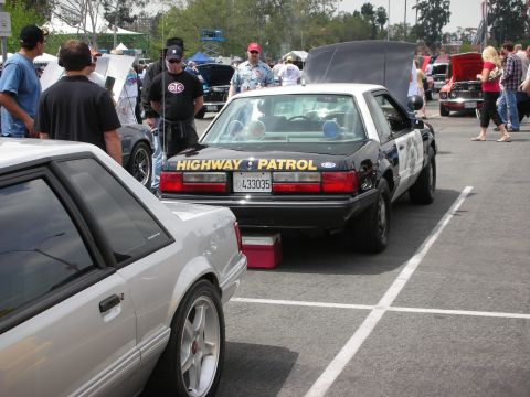 1992 Ford Crown Victoria - A police car, possibly a Ford Mustang, is parked at an outdoor car show with 'HIGHWAY PATROL' visible on the rear.