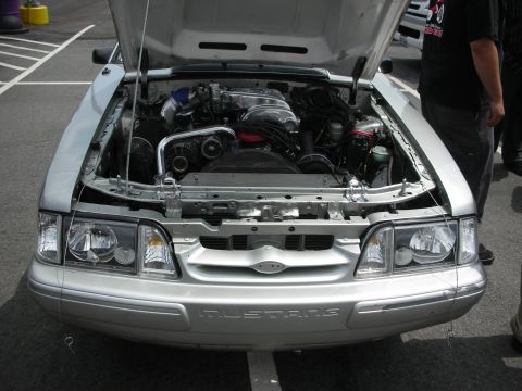 1992 Ford Crown Victoria - Front view of a silver Ford Mustang with its hood open, revealing the engine bay and the "MUSTANG" lettering on the bumper.