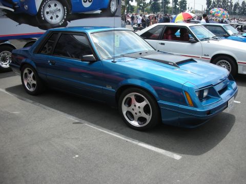 1992 Ford Crown Victoria - A blue coupe with a distinctive body style and aftermarket wheels is parked at an outdoor car show.