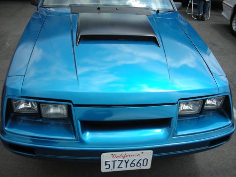 1992 Ford Crown Victoria - Front view of a blue 1987 Ford Mustang with a black hood scoop and California license plate.