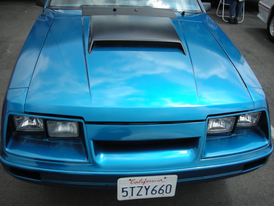 Blue 1987 Ford Mustang front end with black hood scoop and California license plate