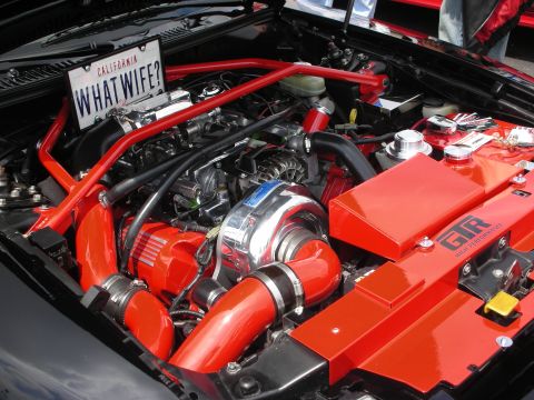 1992 Ford Crown Victoria - Customized engine bay features a prominent turbocharger and bright red accents, with a humorous California license plate.