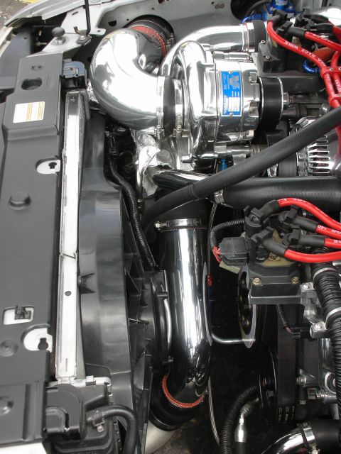1992 Ford Crown Victoria - Close-up view of a polished chrome supercharger and associated engine parts, including red spark plug wires.