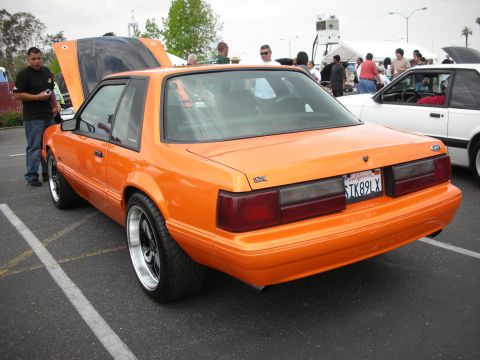 1992 Ford Crown Victoria - Orange 1990 Ford Mustang coupe with aftermarket wheels at a car show.