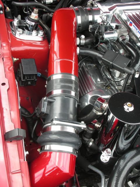 1992 Ford Crown Victoria - Close-up of a red intake tube and chrome engine components within a vehicle's engine bay.