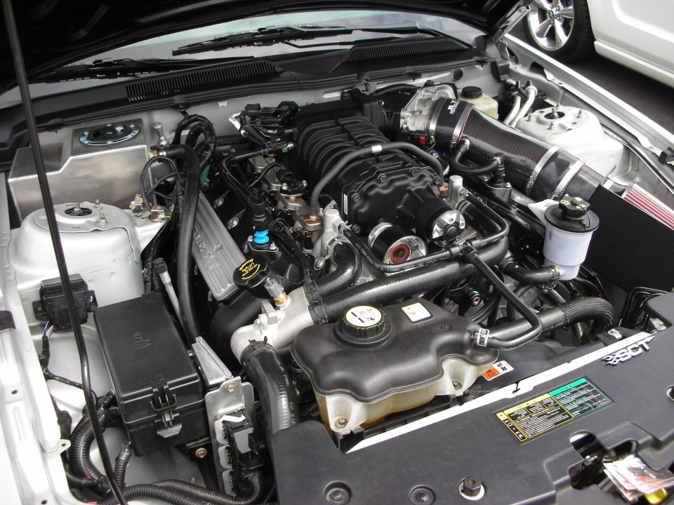 Silver engine bay with black supercharger, carbon fiber intake, and coolant reservoir