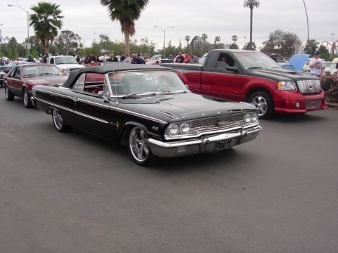 1992 Ford Crown Victoria - A black 1963 Ford Galaxie convertible is seen at a car show, parked next to a red pickup truck.