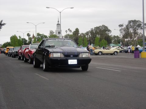 1992 Ford Crown Victoria - A line of cars are parked in a lot, with a black Ford Mustang in the foreground.