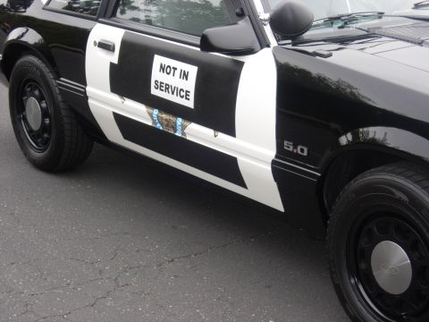 1992 Ford Crown Victoria - This police car, marked "NOT IN SERVICE", displays a 5.0 badge and a damaged police crest on its side.