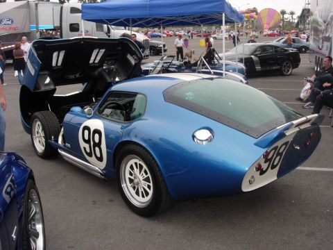 1992 Ford Crown Victoria - A blue Shelby Cobra Daytona Coupe with racing numbers is displayed at an outdoor car show.