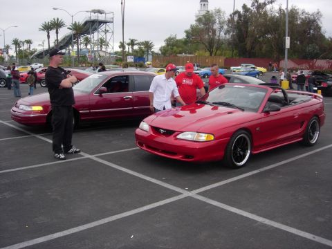 1992 Ford Crown Victoria - A red 1994 Ford Mustang convertible is displayed alongside a maroon sedan at a car show.