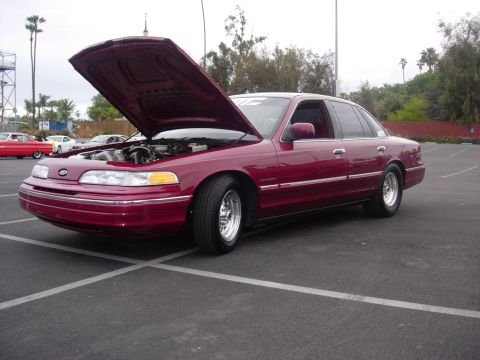 1992 Ford Crown Victoria - A maroon 1992 Ford Crown Victoria is parked with its hood up, revealing the engine bay.