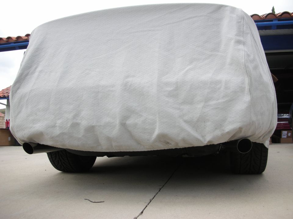 Vehicle under a gray fitted car cover parked on a driveway