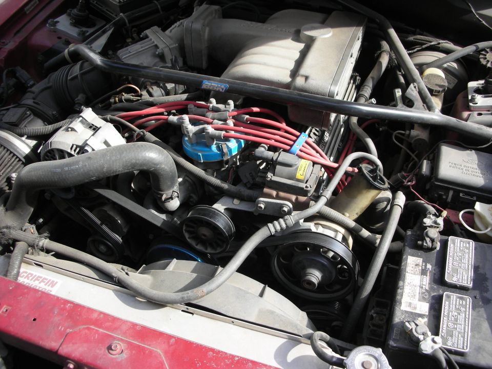 Engine bay of red car with red plug wires and Griffin radiator