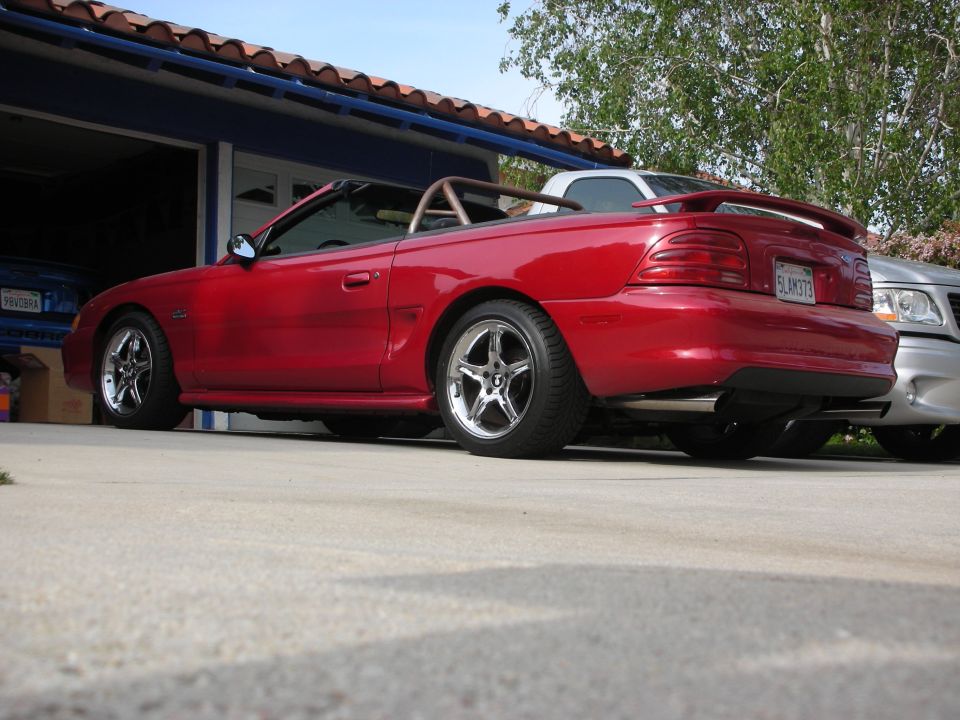Rear side view of red Mustang GT convertible with top down in driveway
