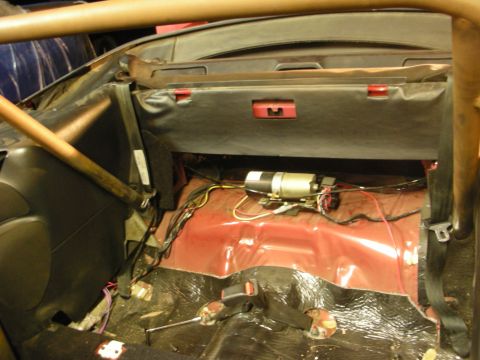 1998 Ford Crown Victoria - Interior of a gutted convertible showing the dashboard, tan roll bar, exposed red floor pan, sound deadening and routed wiring.