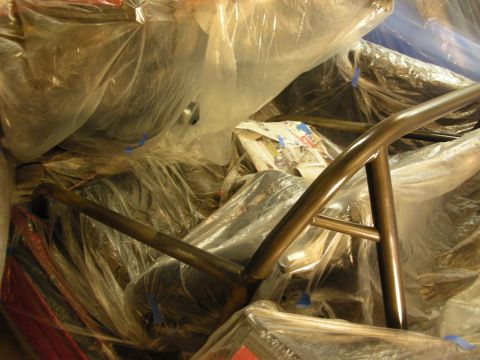 1998 Ford Crown Victoria - Bronze-toned bare metal cage tubing among plastic-wrapped components marked with blue painters tape.