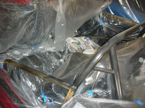 1998 Ford Crown Victoria - Welded metal cage tubing crosses a plastic-sheeted car interior dotted with blue painters tape markers.